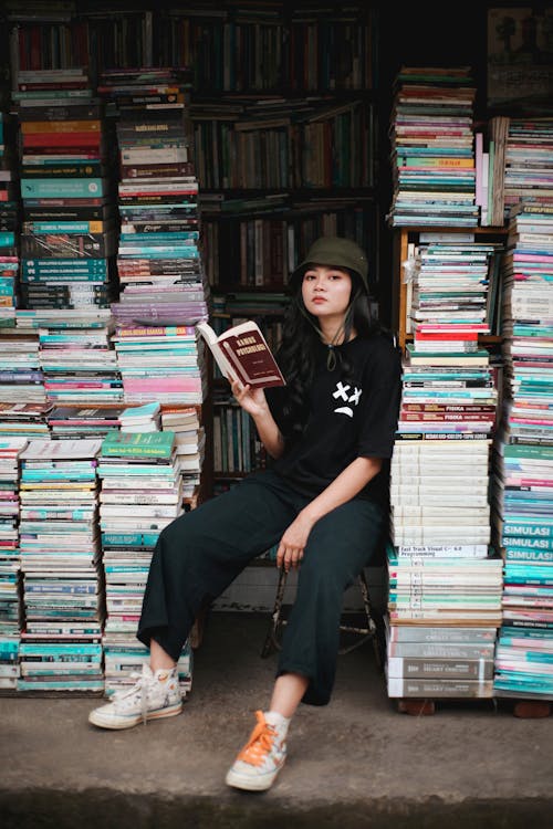 Woman in Black Crew Neck T-shirt Sitting on Books