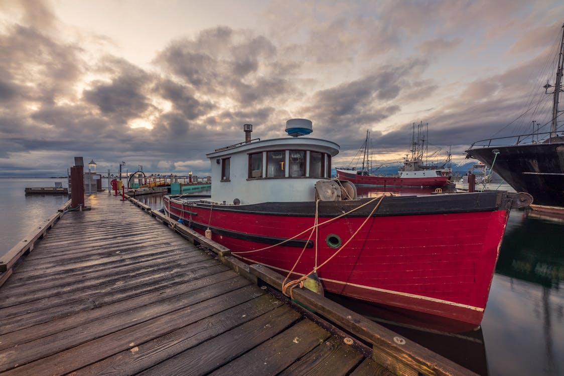 Red and White Boat on Dock Under Cloudy Sky