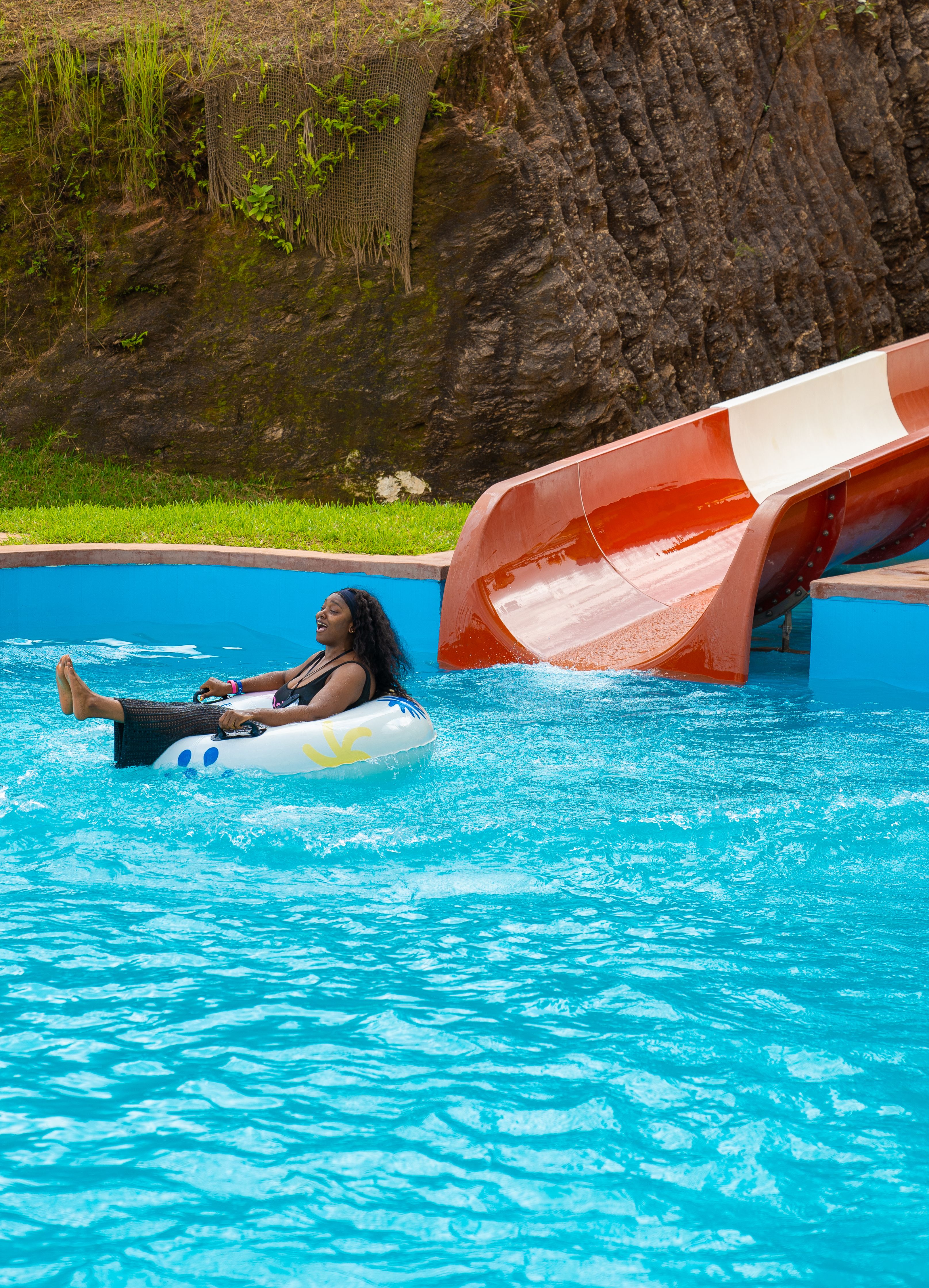 Woman enjoying a ride in an inflatable tube at a vibrant water park slide.