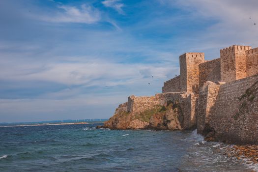 Ancient stone fortress overlooking the blue sea, highlighting medieval architecture by the coast.