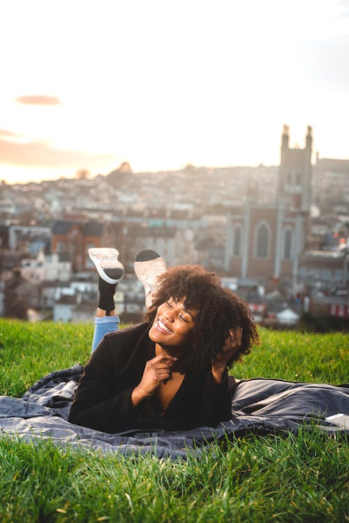 Woman in Black Shirt Lying on Green Grass Field