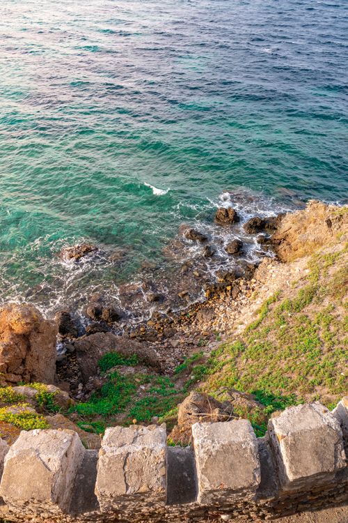 Free View from above of a rocky coastline with blue ocean waves and greenery, evoking a sense of tranquility. Stock Photo