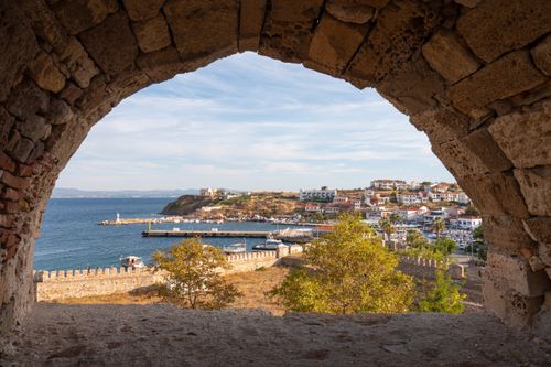 Free View of a charming coastal town through a historical archway with sea and buildings. Stock Photo