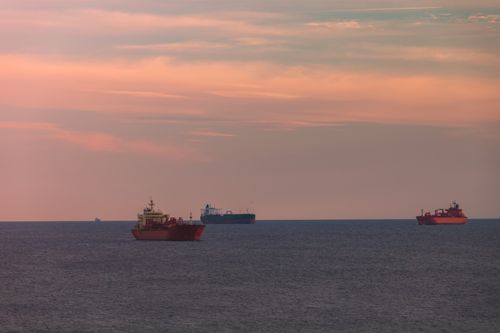 Free Tranquil scene of cargo ships on the ocean with a stunning sunset sky. Stock Photo