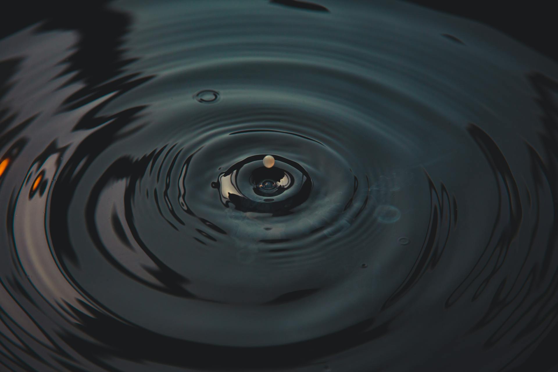 A mesmerizing splash of a water droplet creating ripples on a dark surface.