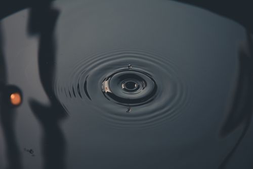 Free A close-up capture of water droplet creating ripples, showcasing nature's tranquility. Stock Photo