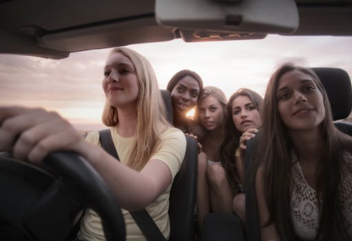Five women sharing a joyful road trip at sunset, symbolizing friendship and adventure.