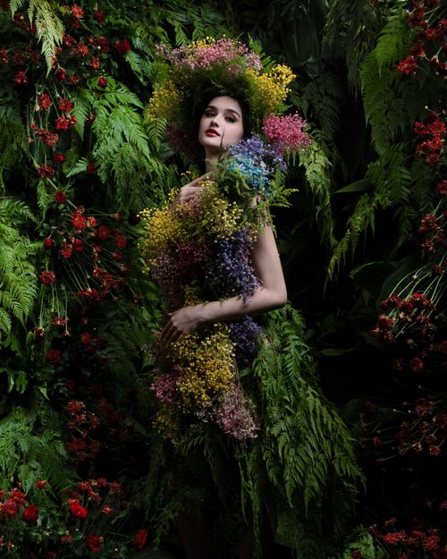 Free Model adorned with vibrant flowers and foliage creates a striking fashion portrait. Stock Photo