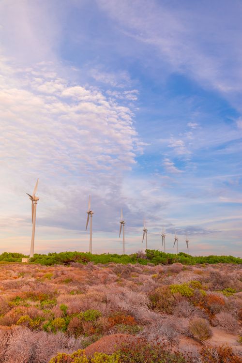 Free A row of wind turbines set against a vibrant desert sky, showcasing renewable energy. Stock Photo