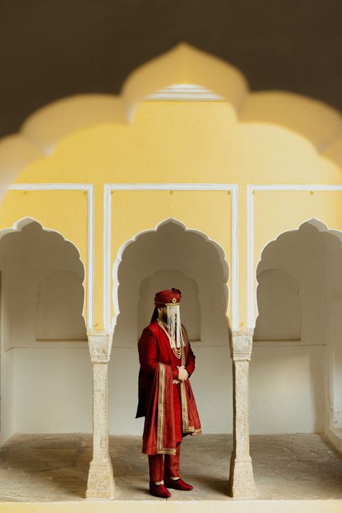 Free A traditional Indian bride standing gracefully in ornate arched architecture. Stock Photo