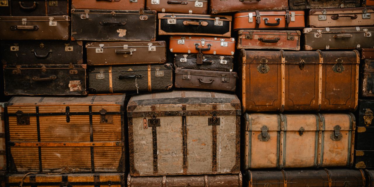 A stack of vintage suitcases creates a retro, travel-themed background.