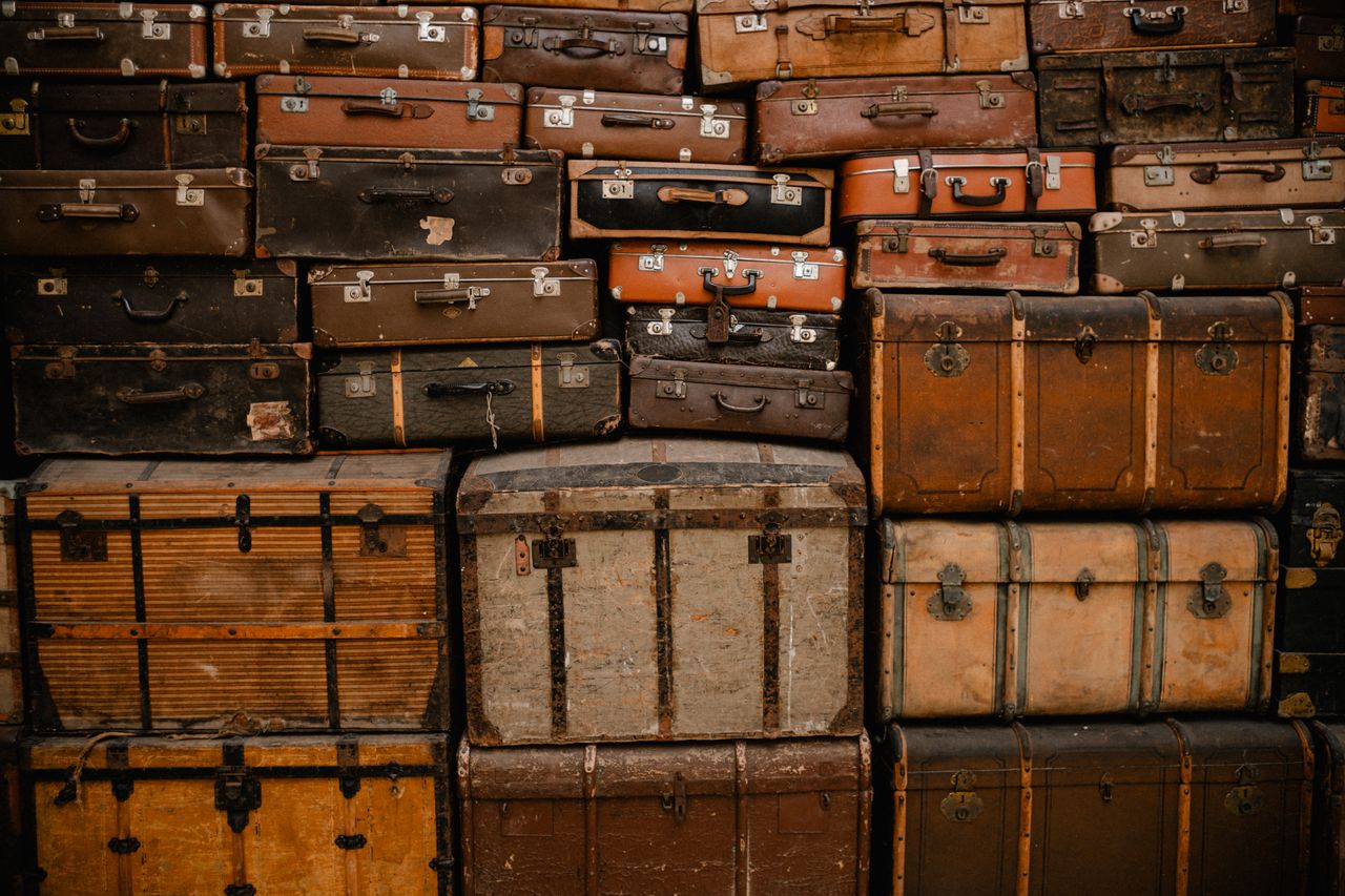 A stack of vintage suitcases creates a retro, travel-themed background.