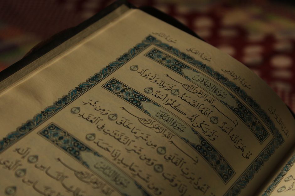 An open Quran showing intricate Arabic calligraphy and decorative designs.
