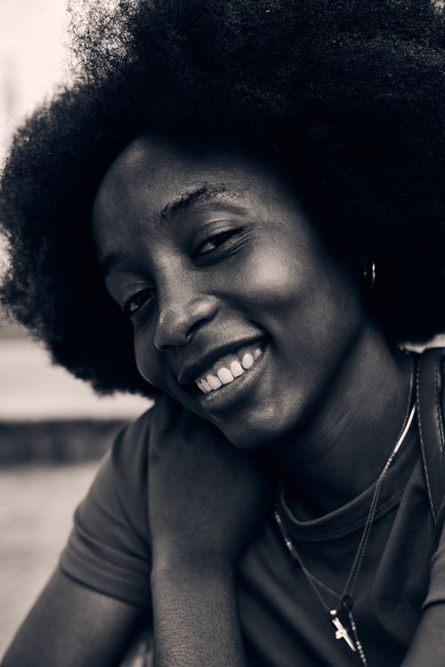 Free A joyful portrait of a young woman with natural hair, captured in soft lighting. Stock Photo