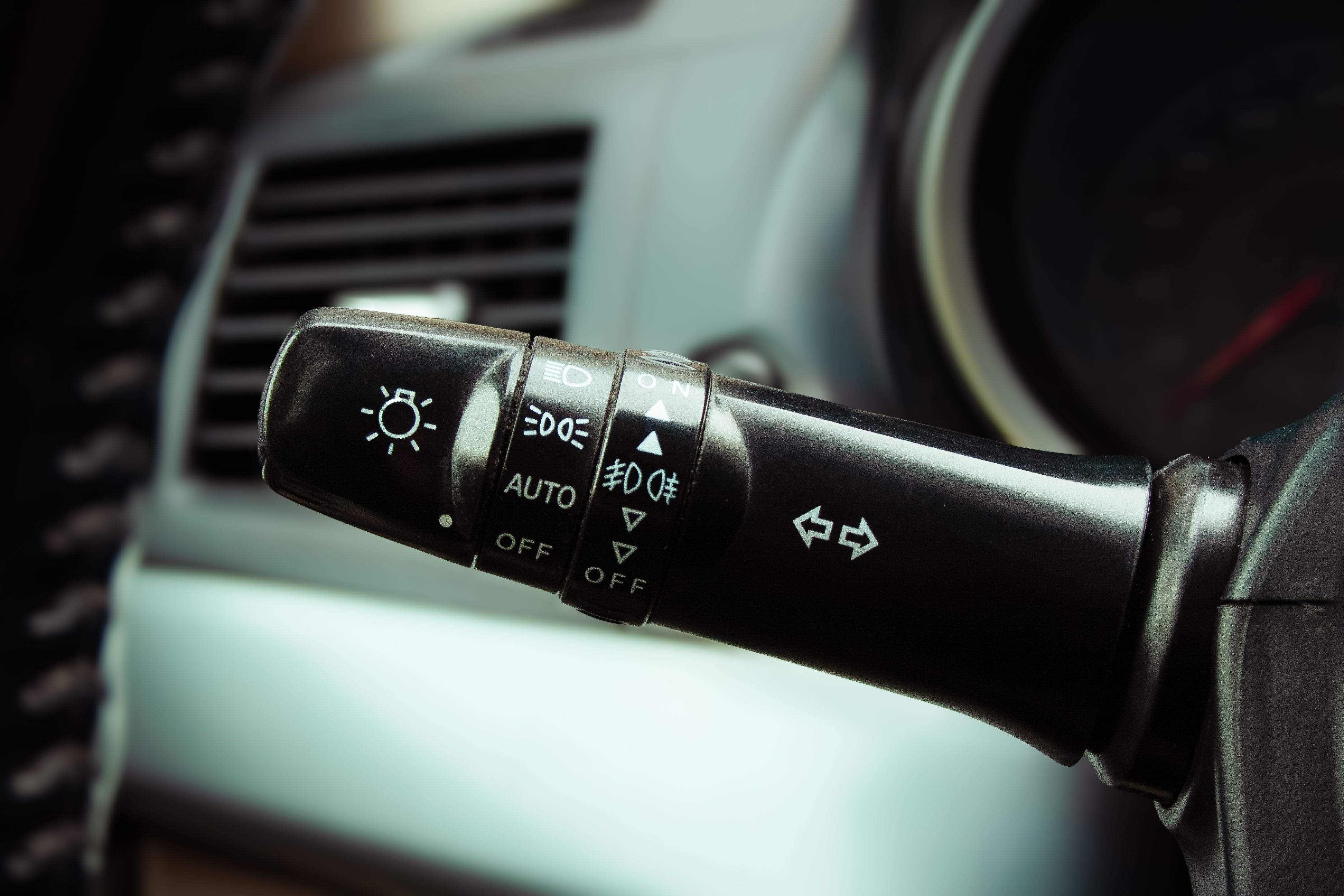 Detailed image of car indicator lever showing light and wiper controls on a steering column inside a vehicle.