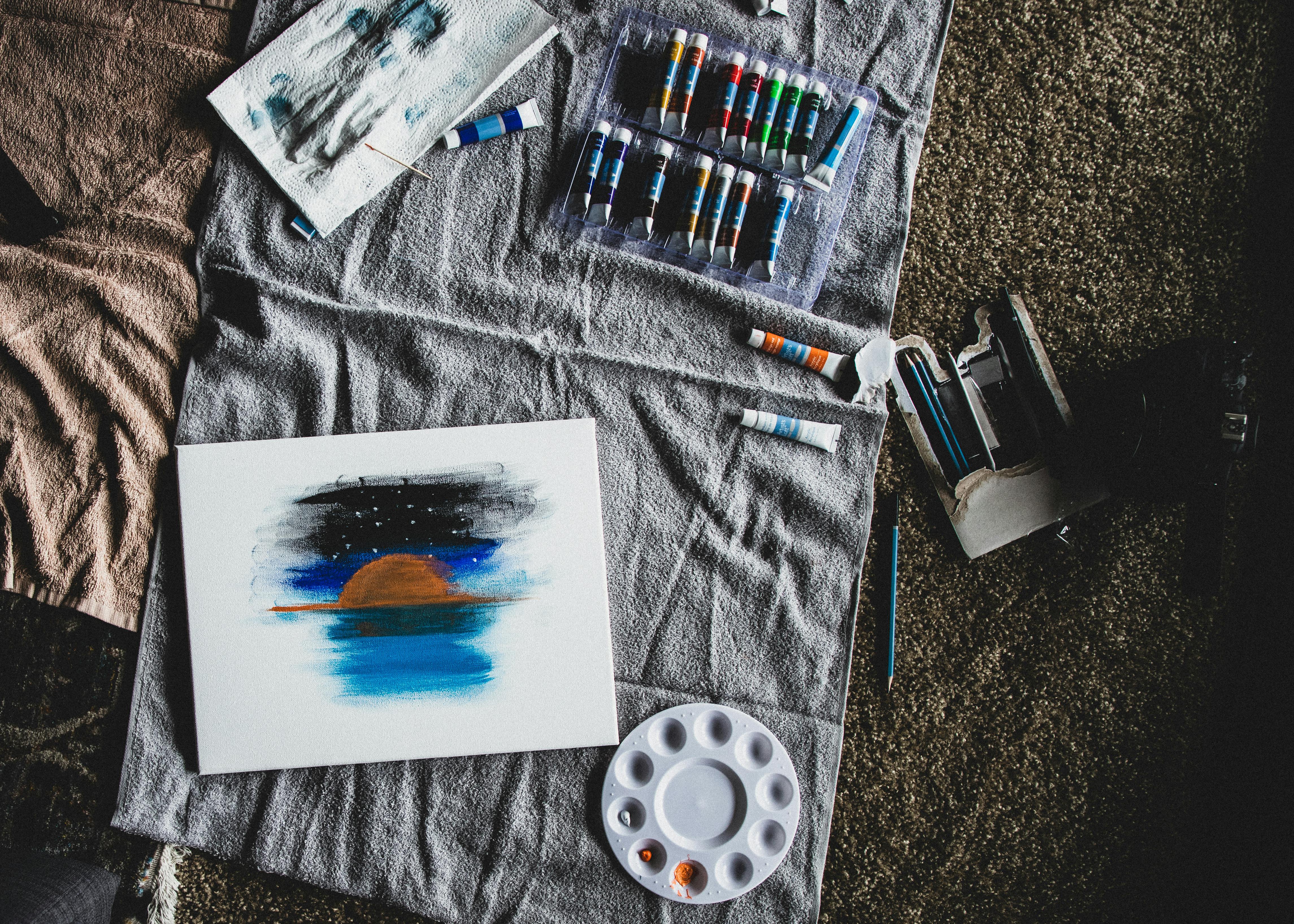 Top view of painting supplies on cloth with artistic canvas and acrylic paints.