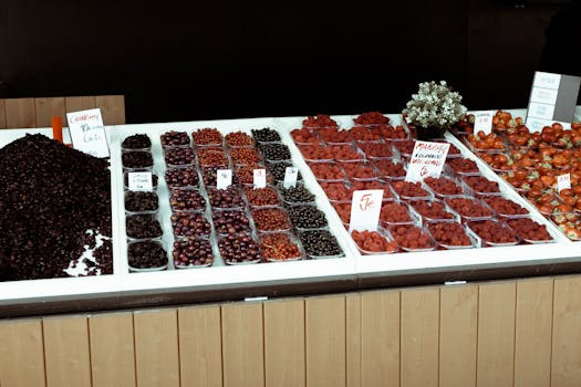 Colorful assortment of fresh berries at a market stall, featuring strawberries, raspberries, and more.