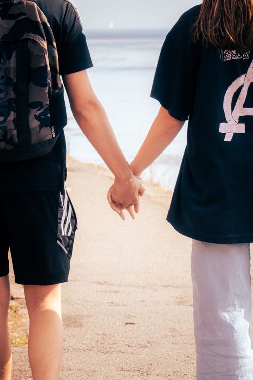 Free A couple holding hands while walking on a scenic seaside path, symbolizing love and togetherness. Stock Photo
