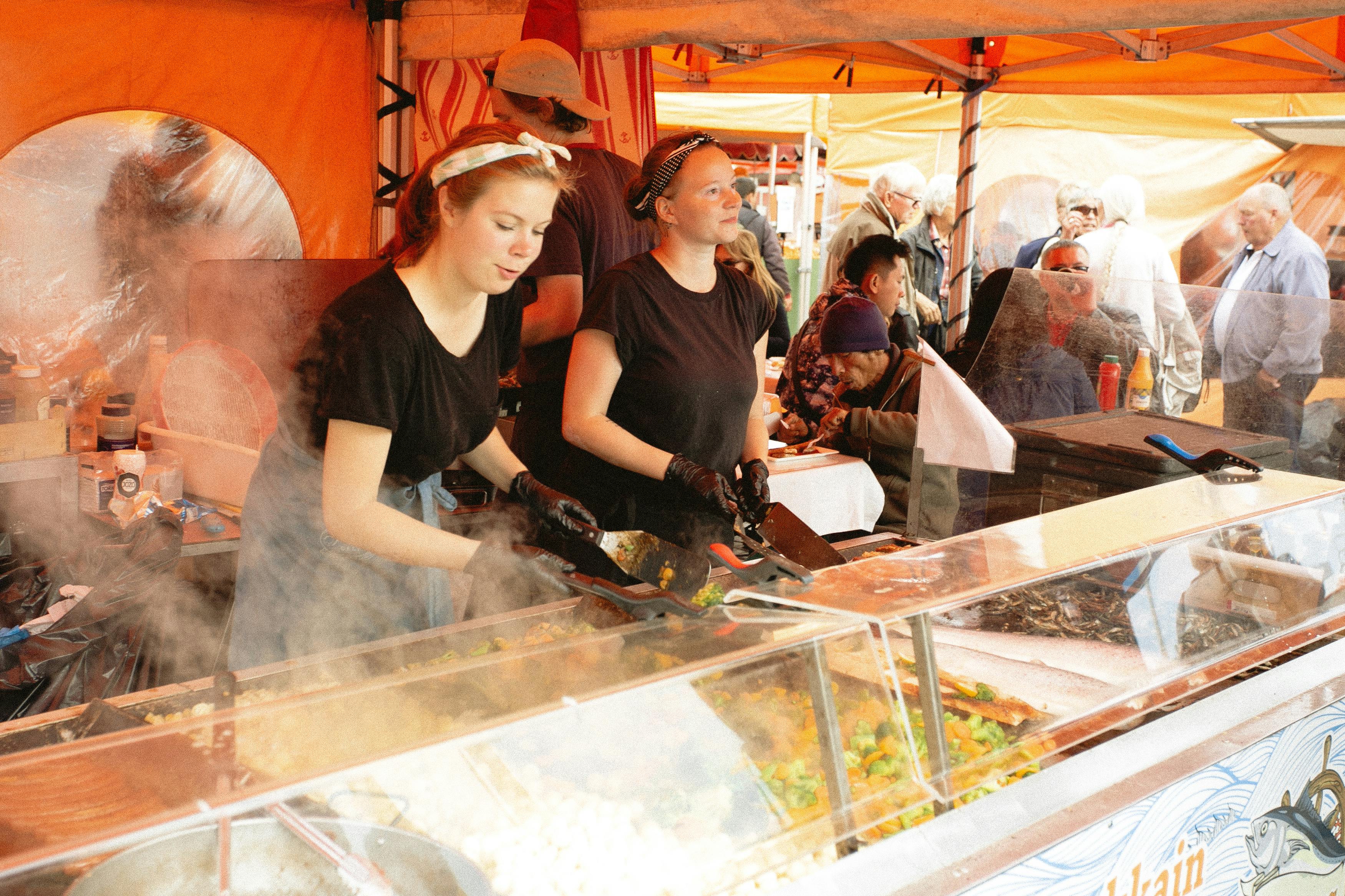 women in black shirt selling food in food stall
