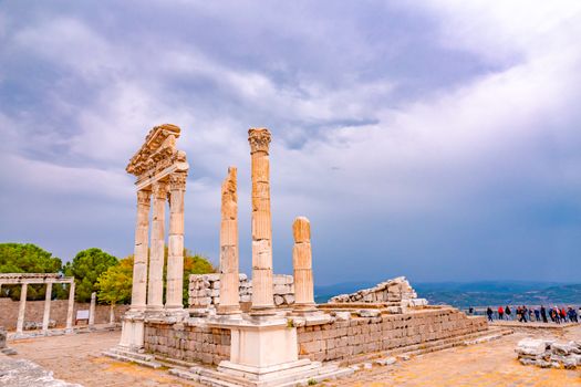 Explore the magnificent ruins of the Temple of Trajan in Pergamon, showcasing ancient architecture against a dramatic sky.