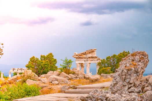 Explore the serene beauty of ancient ruins surrounded by rocky terrain and lush greenery, under a dramatic sky.