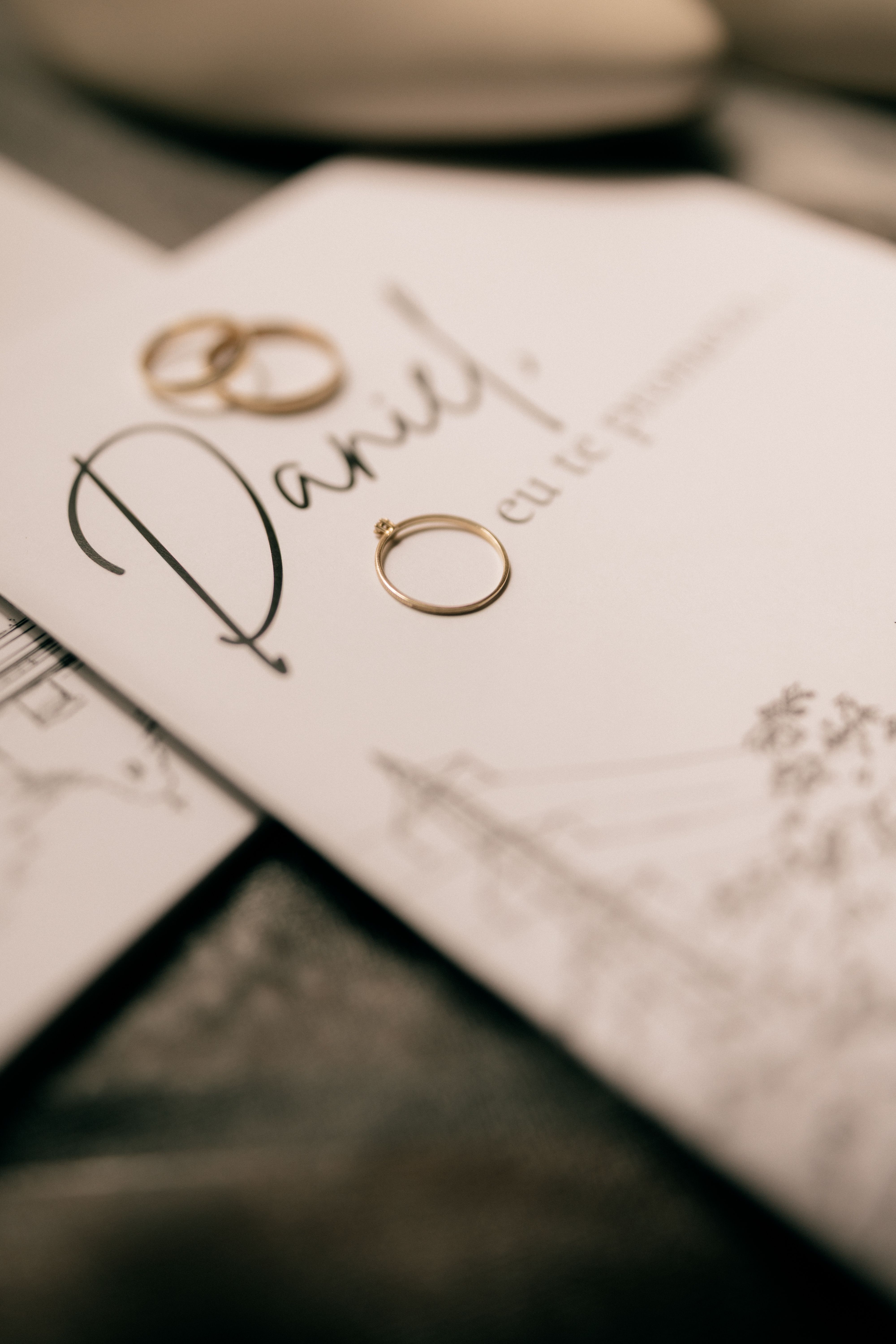 Close-up of wedding invitation and gold rings, showcasing elegance and romance.