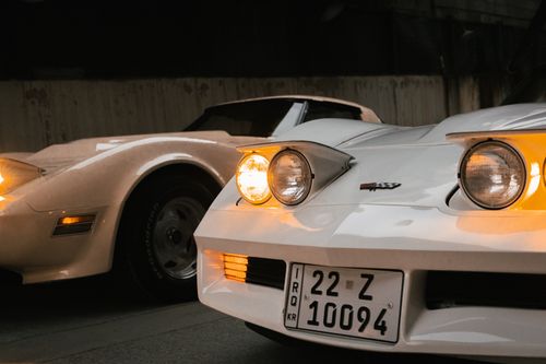 Free Two classic white sports cars parked in an urban area in Erbil, Iraq during twilight. Stock Photo