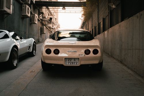 Free Classic Corvette car parked in a narrow, industrial alleyway in Erbil, Iraq at sunset. Stock Photo