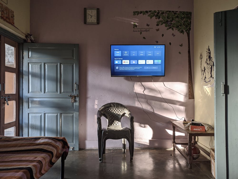 Black Flat Screen Tv Turned on Near Green Plastic Armchair