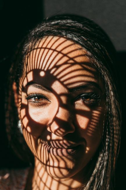 A woman's face is adorned with complex shadow patterns, providing an artistic and intriguing portrait.