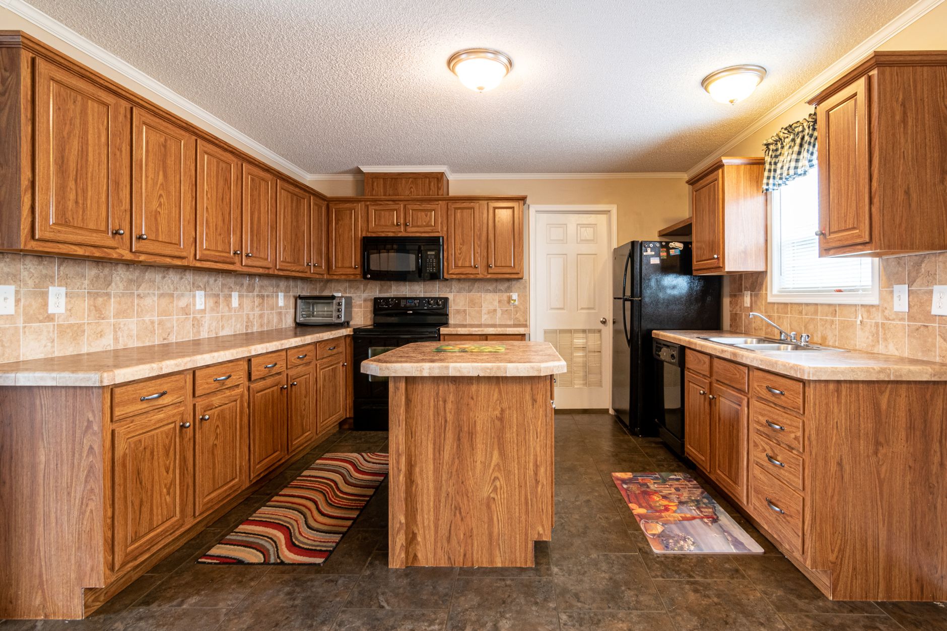 Spacious kitchen interior featuring wooden cabinets, marble countertop, and modern appliances.