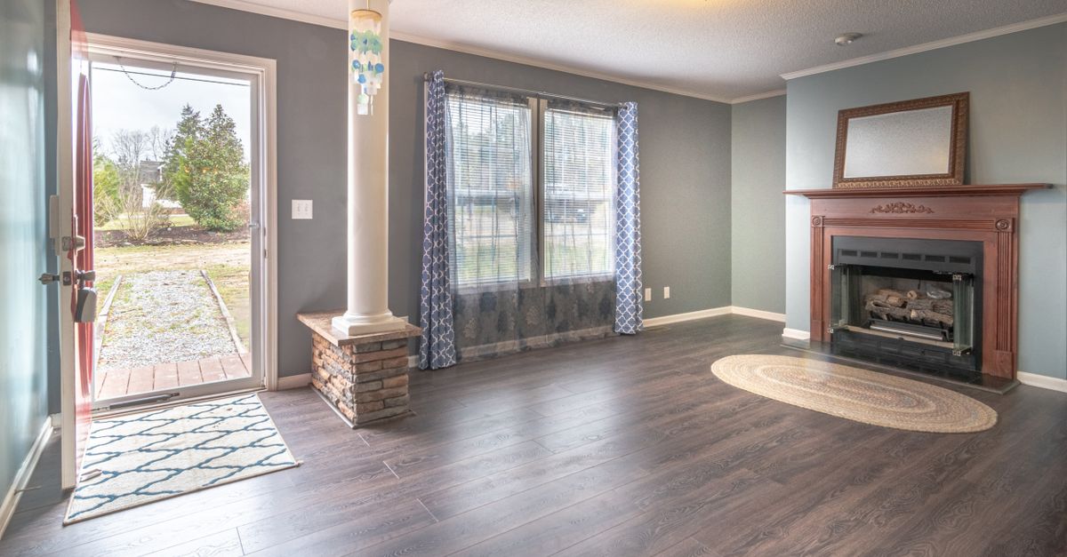 Inviting living room with fireplace, large windows, and open door leading outside.