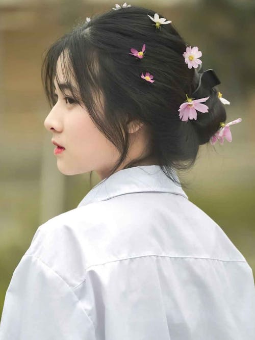 Woman in White Shirt With Pink Flowers on Her Hair