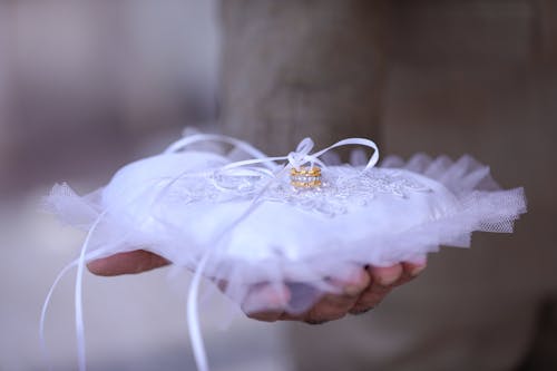 Person Holding Pillow with Gold Ring