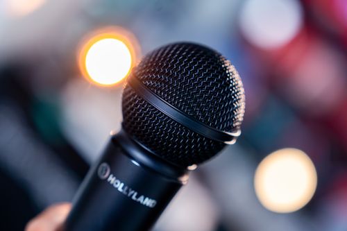 Free A detailed close-up of a black microphone against a colorful bokeh background. Stock Photo