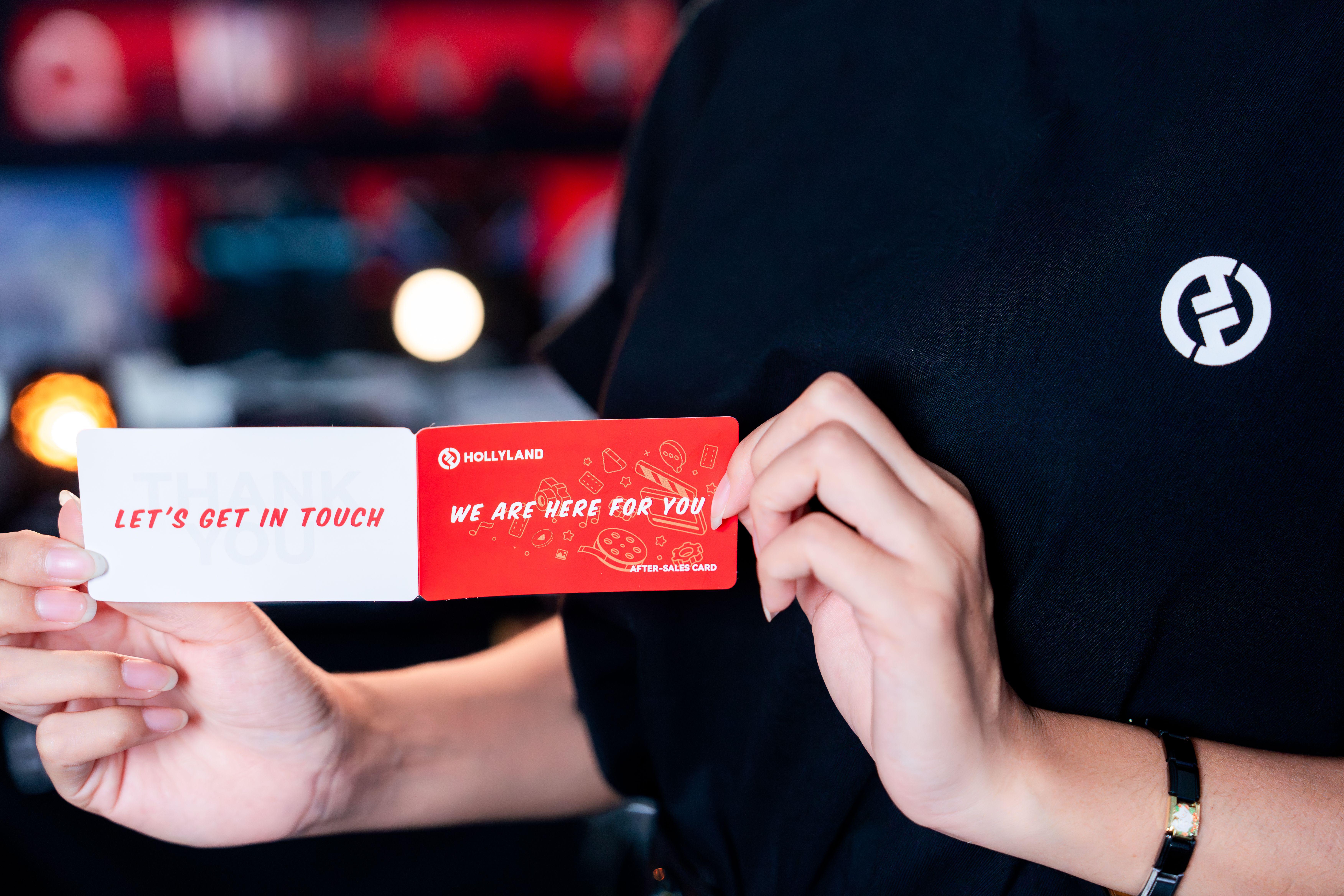 Close-up of hands holding marketing contact cards in a business setting.