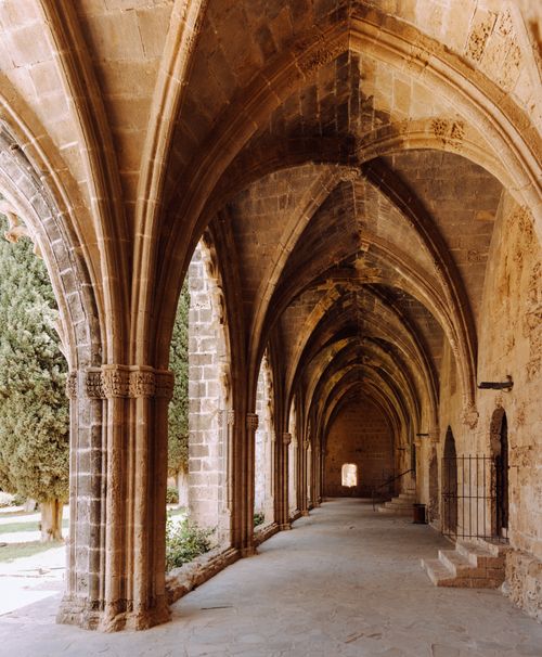 Free Sunlit gothic cloister with intricate stone arches casting dramatic shadows. Stock Photo