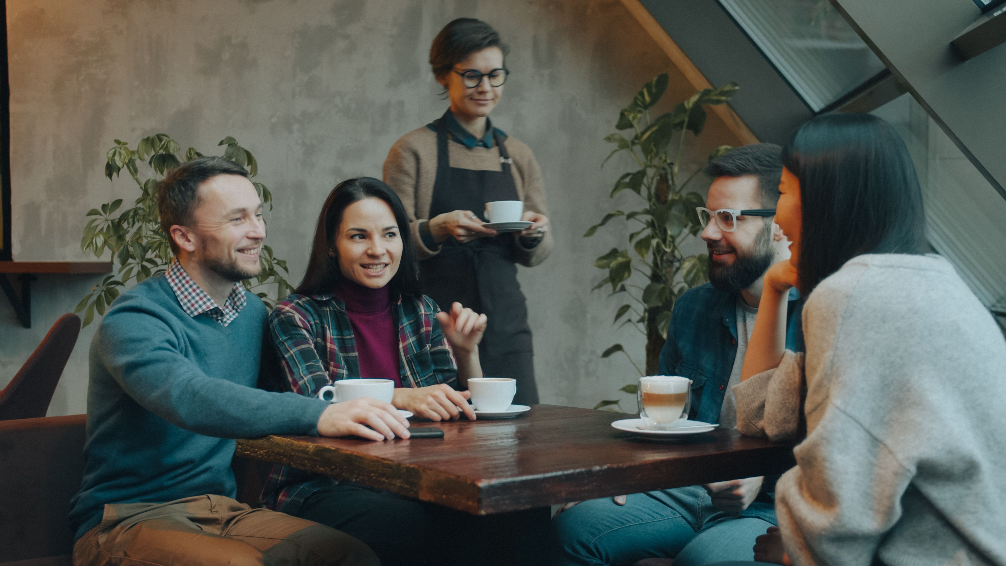 A group of friends enjoying coffee and conversation in a cozy indoor cafe, captured in a warm and relaxed atmosphere.