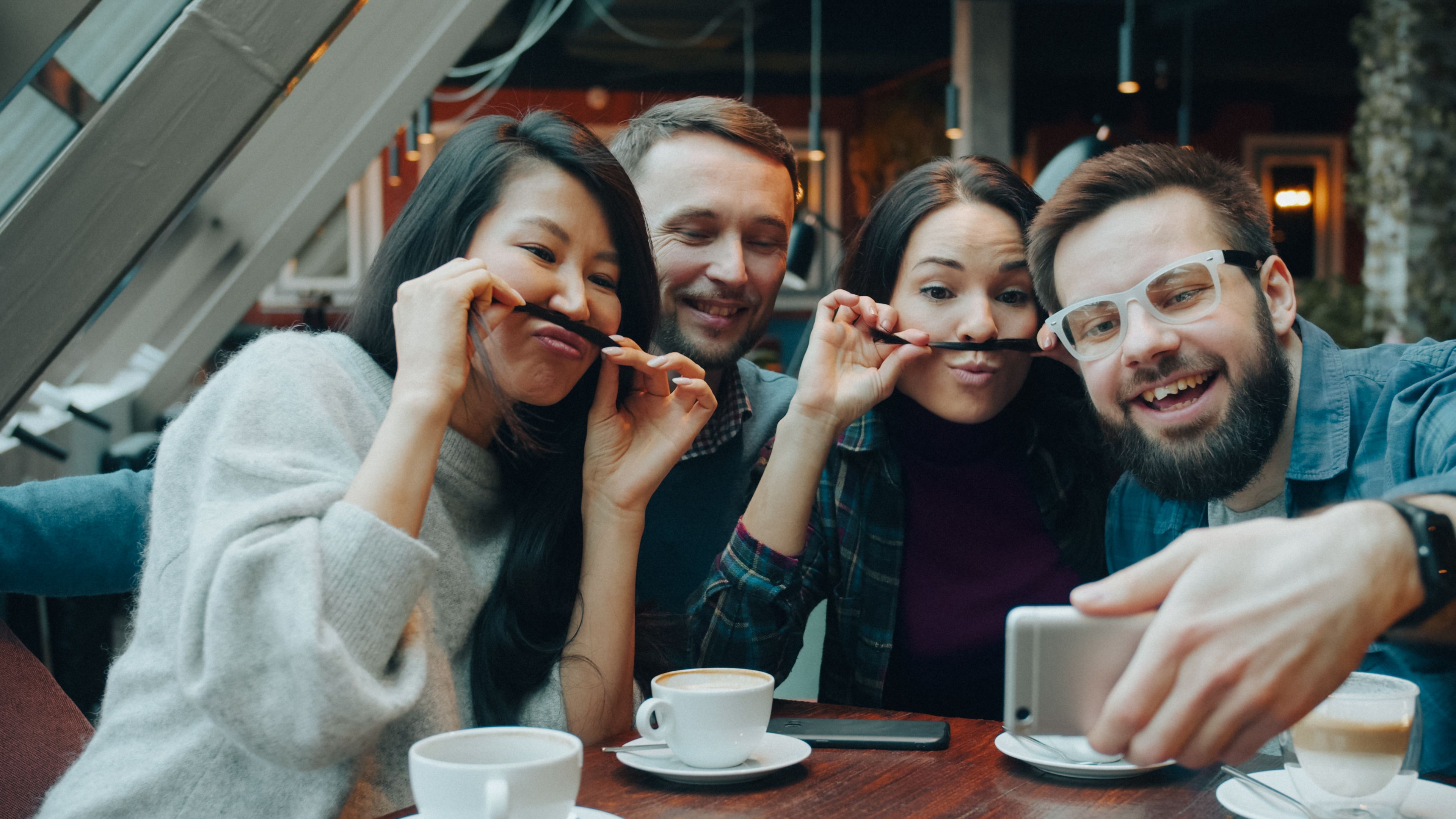 Group of friends enjoying a coffee break indoors while taking a playful selfie together.