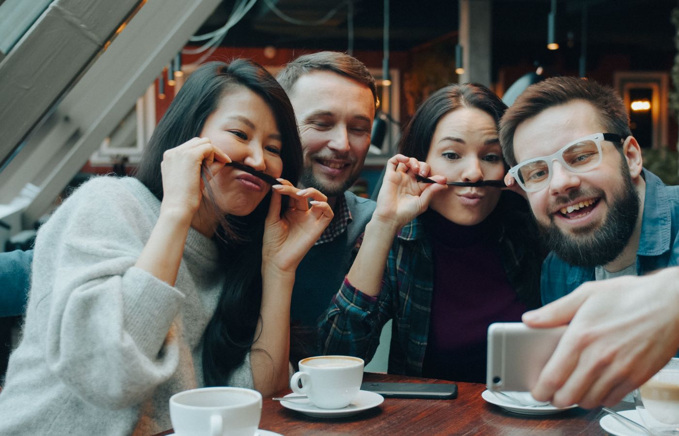 Group of friends enjoying a coffee break indoors while taking a playful selfie together.