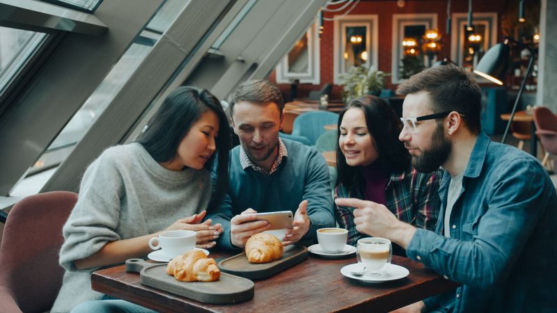 Friends sharing coffee and croissants at a cafe