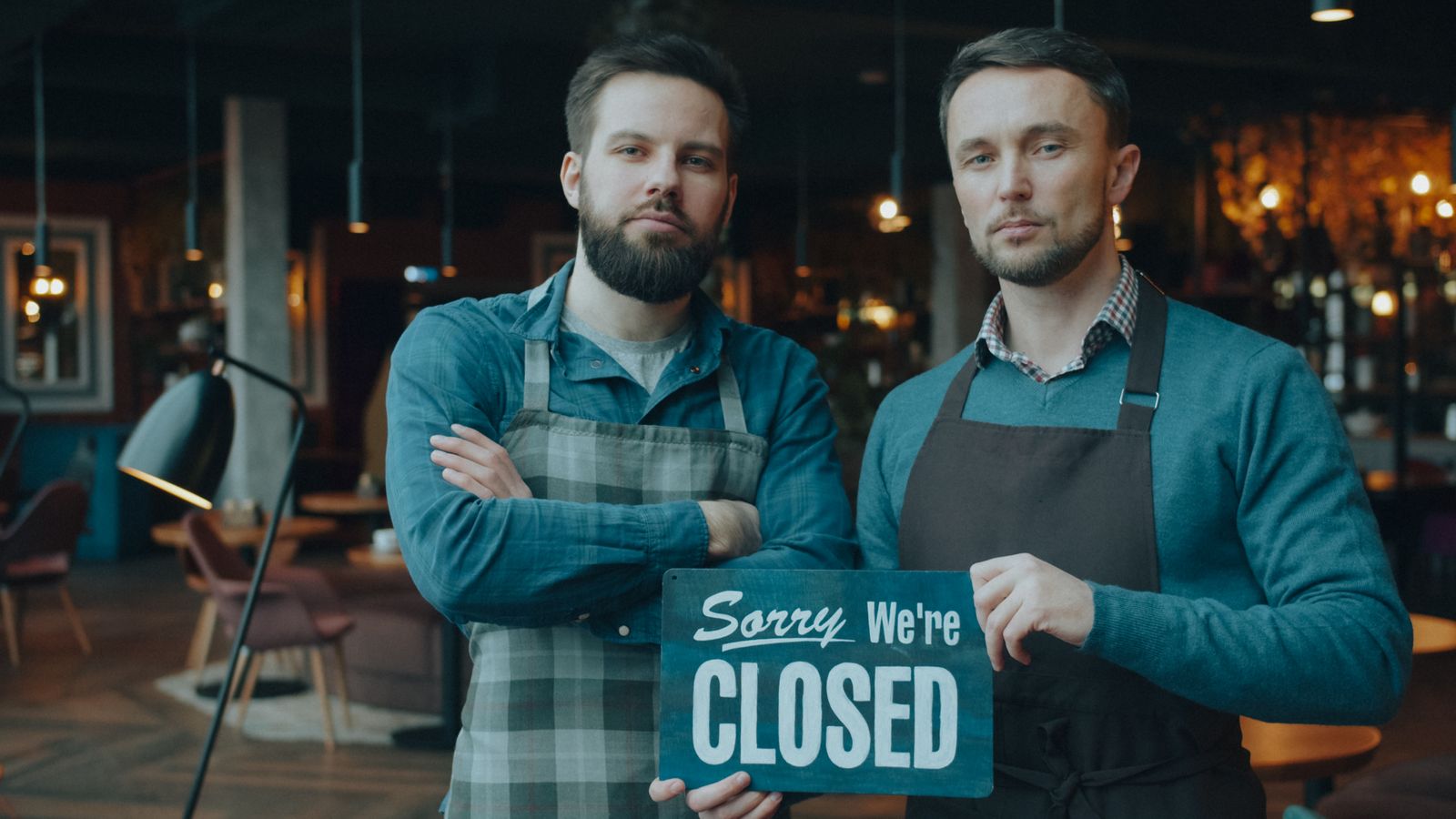 Two shop owners holding a closed sign