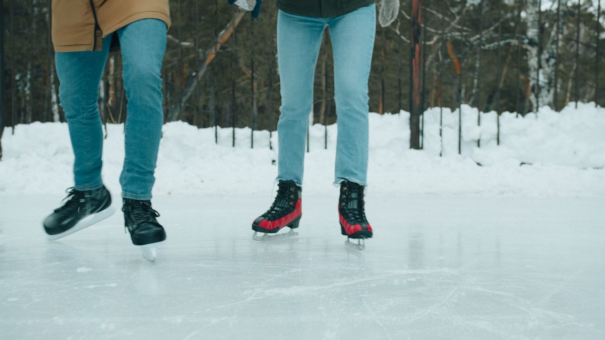 Two people ice skating on an outdoor rink