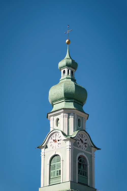 Free Close-up of a green-roofed clock tower in Toblach, Italy under a clear blue sky. Stock Photo