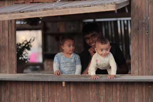 Free Two smiling children with an adult in a rustic wooden setting. Outdoors, candid moment. Stock Photo