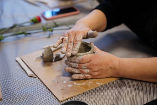 Free Hands shaping clay into a pot, showcasing artistic pottery and craftsmanship in a workshop setting. Stock Photo