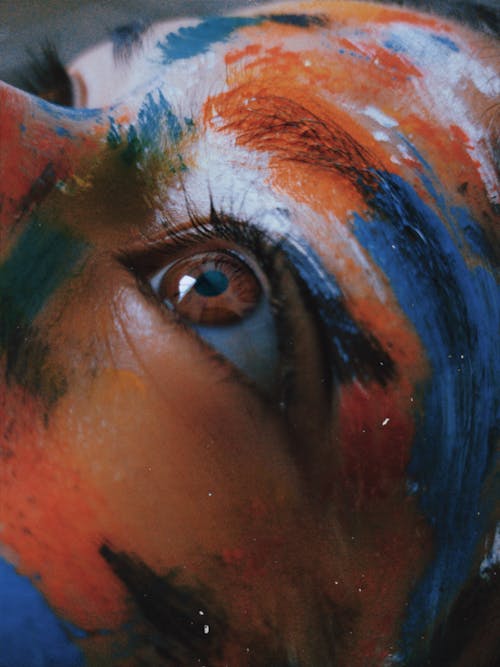 Persons Eye With Blue and Orange Color Face Paint