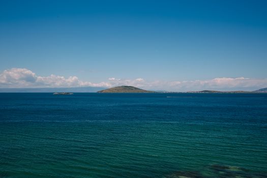 A tranquil island surrounded by deep blue waters under a bright sky.