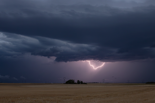 Free Dramatic storm clouds with visible lightning across a countryside landscape. Stock Photo