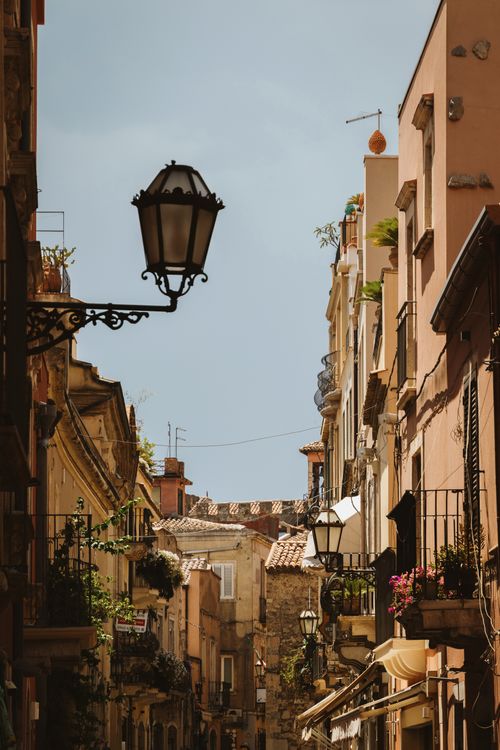 Free Discover a quaint Sicilian alley with rustic buildings and classic street lamps under a clear sky. Stock Photo
